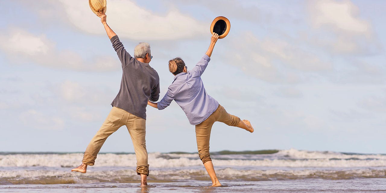 older couple looking at the ocean jumping for joy